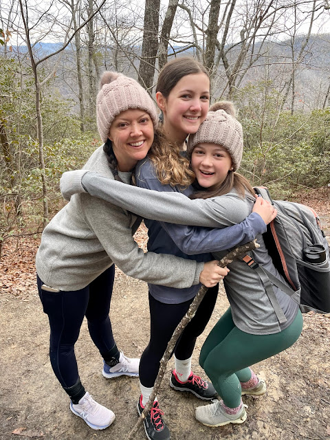 mom and 2 teen girls hugging on a hike