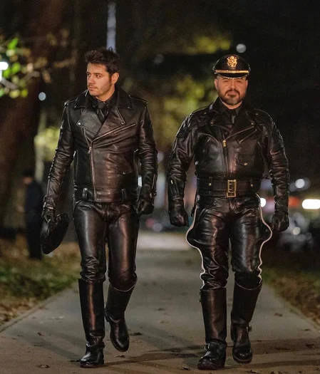 Straight on view of two leather men in full gear walking down the road toward the camera