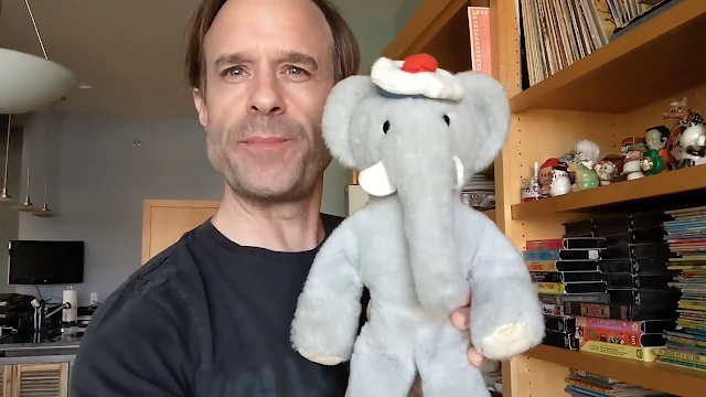 picture of man holding a stuffed elephant doll