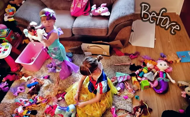 A messy front room with 2 girls playing in it dressed as Disney princesses