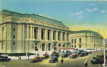 Scan of a hand-colored photo postcard. Two Neo-classical buildings on Van Ness Ave., SF, the War Memorial Opera House and the Veterans Building. Also on the street, a number of 1930s automobiles.