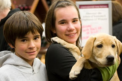 Two puppy raisers and their pup at the Dogs on the Square event