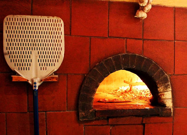 pizza being cooked in a wood fired brick oven