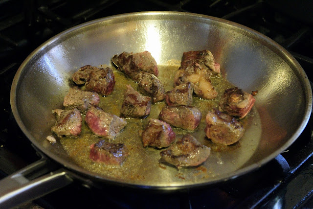 The cubed and seasoned beef, in the skillet, browning.