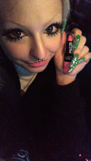 Ray takes a selfie wearing and holding their new lipstick, which is bright bubblegum pink, they are looking at the camera