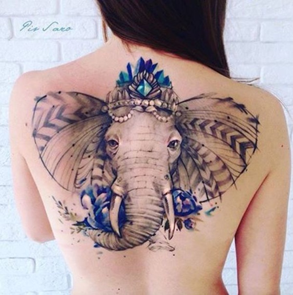 Um elefante veste uma ruiva coroa e está decorado com tons de azul, pérolas, e um padrão de repetição setas junto aos ouvidos.