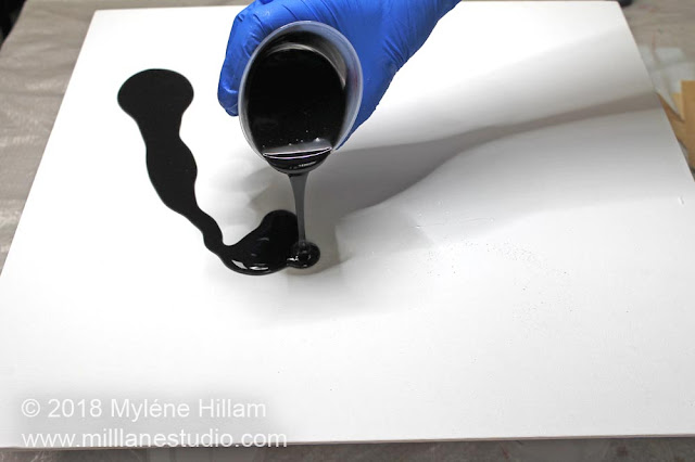 Pouring black resin onto the canvas