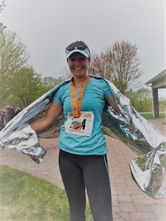 Runner after crossing the marathon finish line, wearing medal, race bib, and heat wrap