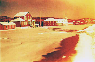 Sanmaur - L'école, le presbytère, l'église, le magasin Thériault, fin d'apràs-midi d'hiver, vers 1953. Photo aimablement retouchée par Paul-Émile Larivière