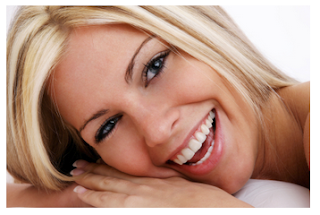 Photo of a blonde-haired woman smiling and showing off her white porcelain veneers