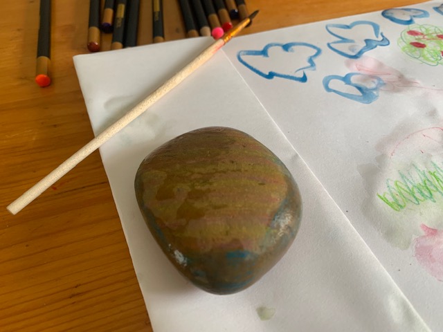 A pebble painted with stripes, on a piece of white paper