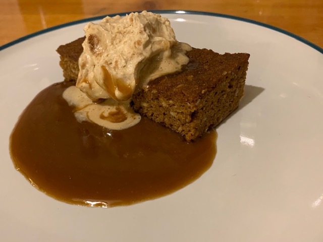 Slab of parkin with caramel sauce and apple crumble cream quenelle