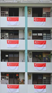 An apartment block with the red and white flag of Singapore hanging from each window