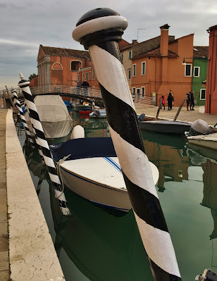 Striped poles used to tie up boats on Burano's main canal, Burano, Italy