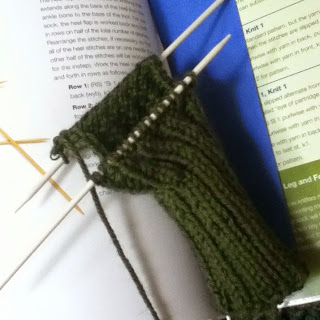 Forest green ribbed leg and heel flap for sock on two double-pointed knitting needles