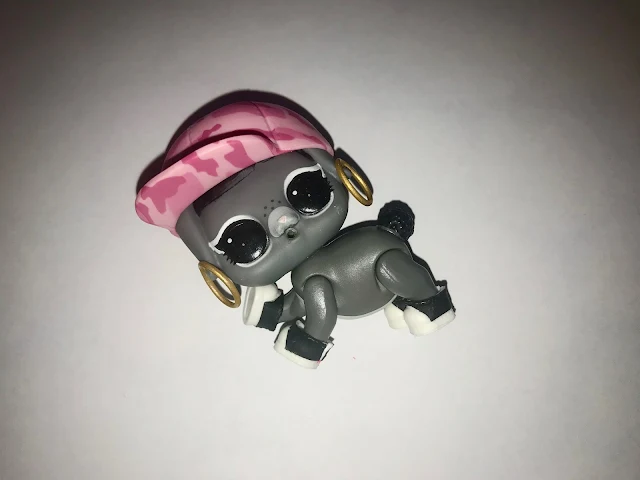 Close up of the pet in our LOL Surprise pet ball. She has a pink camouflage baseball cap, large hoop earrings and sneakers on her grey body