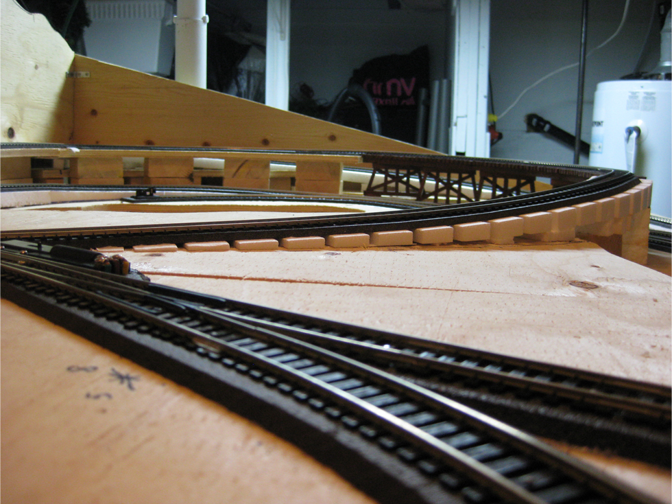 A reduced track grade leading down from a wooden train trestle