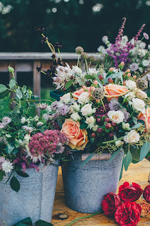 Two metal buckets filled with a variety of multi-colored flowers. Photo by Annie Spratt on Unsplash.