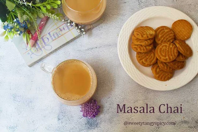 A cup of masala chai served with cookies