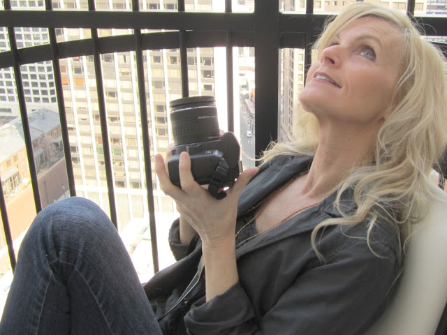 blonde holding camera aimed at sky on waldorf astoria balcony by Hello Lovely Studio