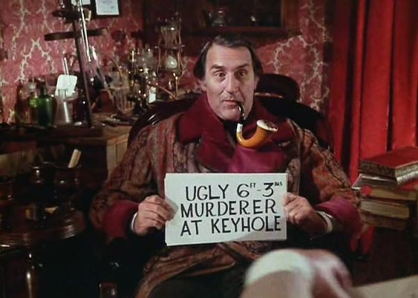 Douglas Wilmer as Sherlock Holmes holding up a hand written sign