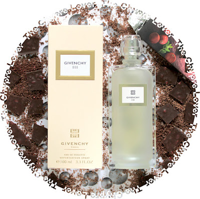 The bottle and box of Givenchy III by Givenchy lying flat on a picture with water bubbles, next to pieces of chocolate, some of which grated