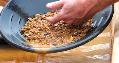A gold panning tray filled with mud and rocks.