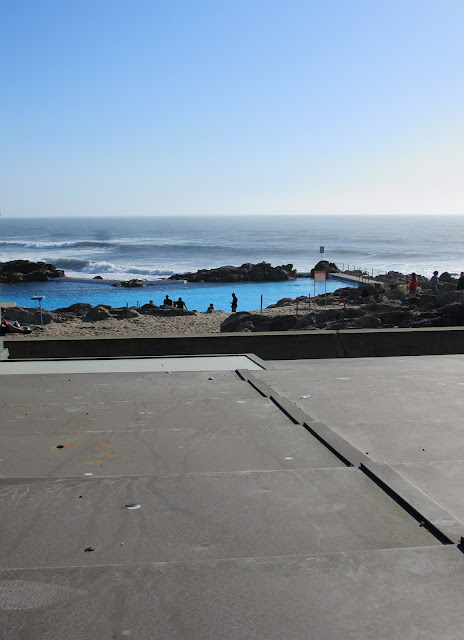 Piscina entre rochas e o mar e algumas pessoas ao redor