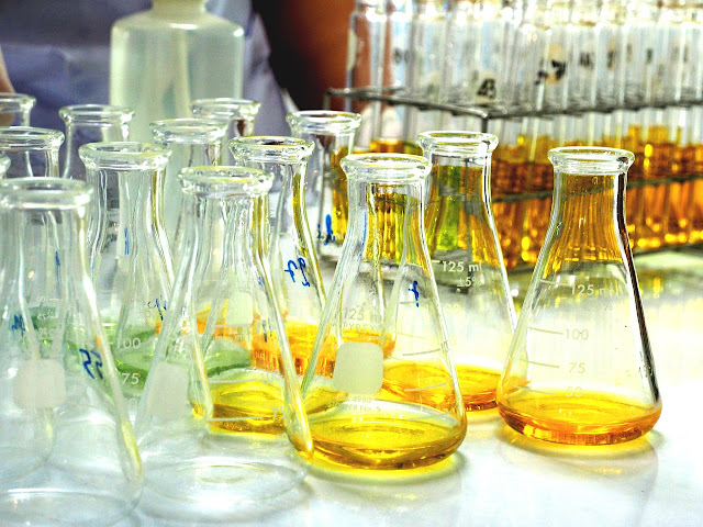 A group of clear glass test tubes, with some samples of a brown liquid chemical.