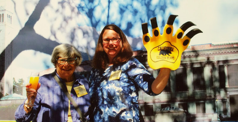 Photo of me and mom at Parents and Alumni Weekend. Mom is holding a champagne glass with orange juice and I am wearing a large foam Go Bears claw.
