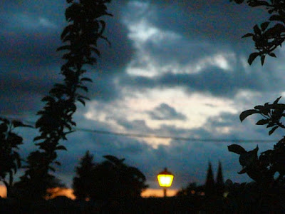 paisaje nocturno: claro entre nubes, sombras de árboles y farola