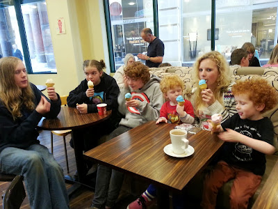 6 children of various ages seated at a long wooden table eating exciting ice creams