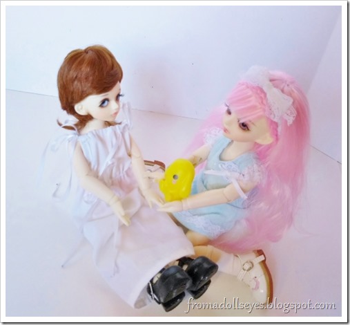 The pink haired ball jointed doll is giving the new doll a cute yellow bunny toy as a welcome present.