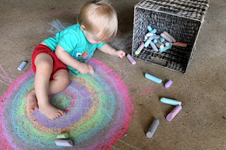 A boy drawing on the ground with colorful chalks