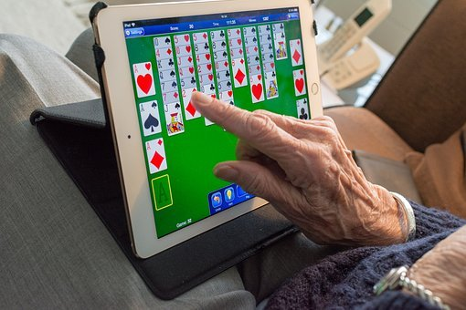 A senior woman playing solitaire on a tablet