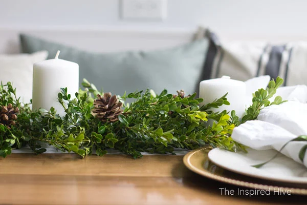 How to decorate a table for Christmas on a budget! Beautiful farmhouse winter tablescape using a boxwood runner as a DIY centerpiece.