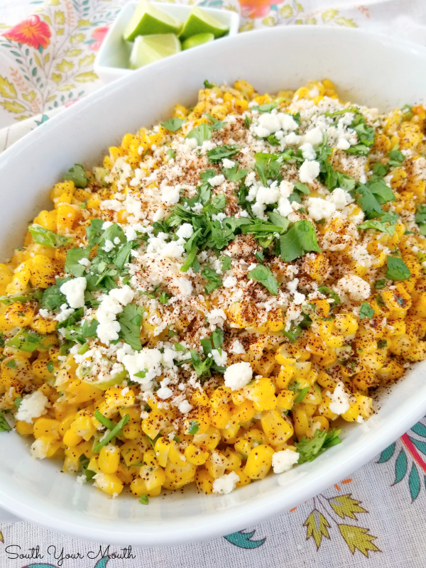 Mexican Street Corn! An easy recipe for Esquites - or Mexican Street Corn - served off the cob as a side dish or warm salad with Mexican crumbling cheese, a creamy spread, fresh cilantro and chili powder.