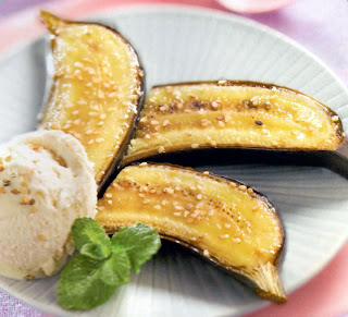 honey baked bananas with sesame seeds. Halved bananas, baked with honey, topped with sesame seeds and served with ice cream and a sprig of mint