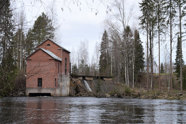 Vanha, punatiilinen vesivoimalarakennus padon partaalla.