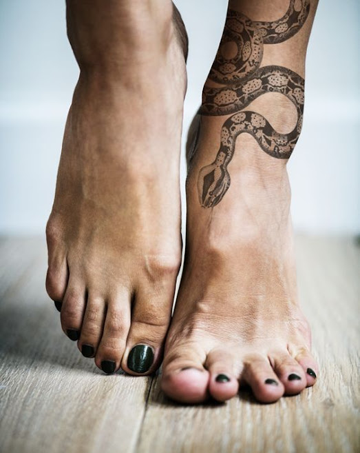 black-ink-snake-on-woman's-ankle-tattoo