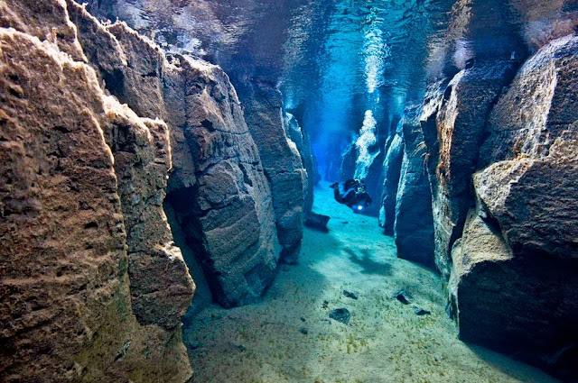 Scuba diver swimming in shallow underwater crevice