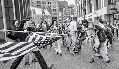 anti-busing protester threatend African American man with the American Flag in Boston, 1976