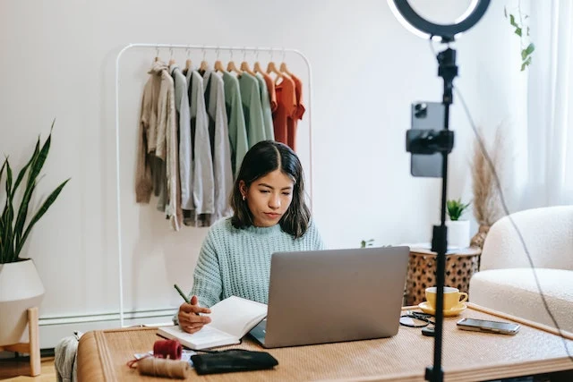 Una mujer sonriente con un portátil en el regazo escribiendo en su blog de estilo de vida.