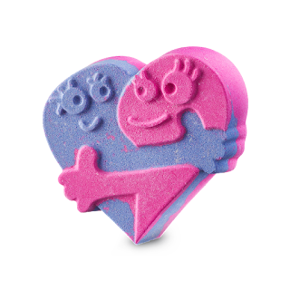 A big lightly purple heart shaped bath bomb with two people hugging engraved onto it on a bright background