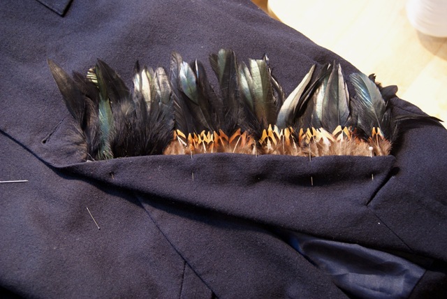 Once you have all your items together you will need to measure the length of the lapel of your jacket and cut your feather trims to match that length. Now you will need to use your creative eye to layer your feathers however you like. Once you've got your desired look, you will need to pin the ribbon of the feather trim to the under side of your lapel.