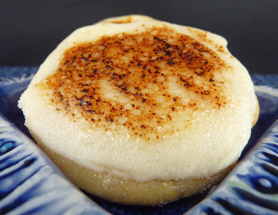 Creme Brulee Cookie: a simple cookie topped with cream cheese frosting. Top with sugar then carmelized with a kitchen torch. Photographed on a blue plate.