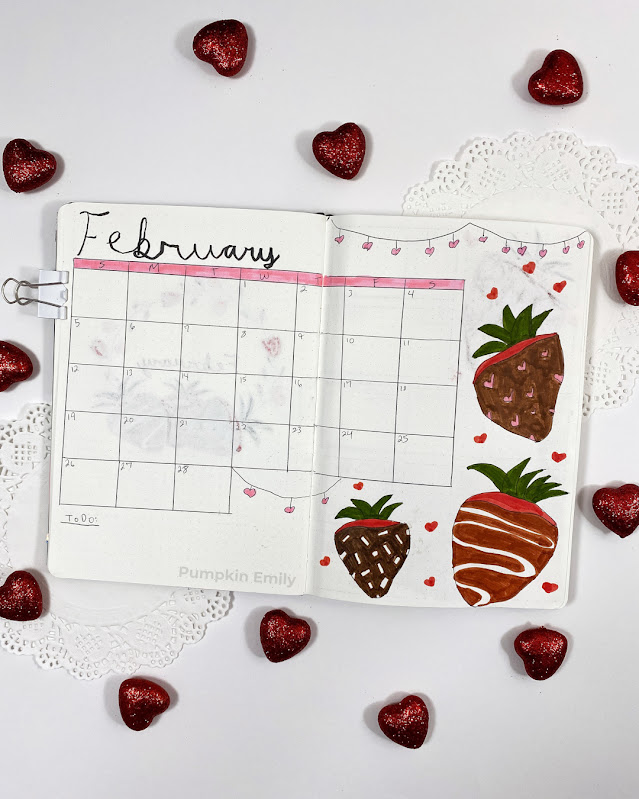A two page February bullet journal calendar page with chocolate covered strawberries.