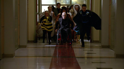 The glee kids dressed as various made up superheroes while running down a school hallway