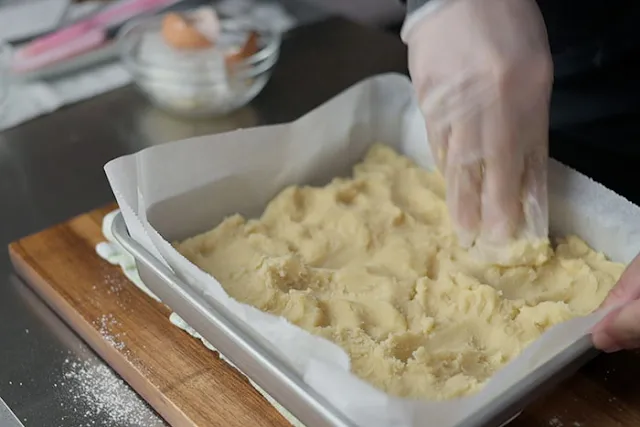 Spread the dough onto an 8 inch by 8 inch baking pan lines with greaseproof paper.
