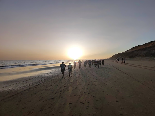 Corredores en la playa con puesta de sol